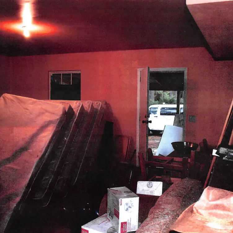 Une pièce rouge faiblement éclairée remplie de matelas empilés verticalement.