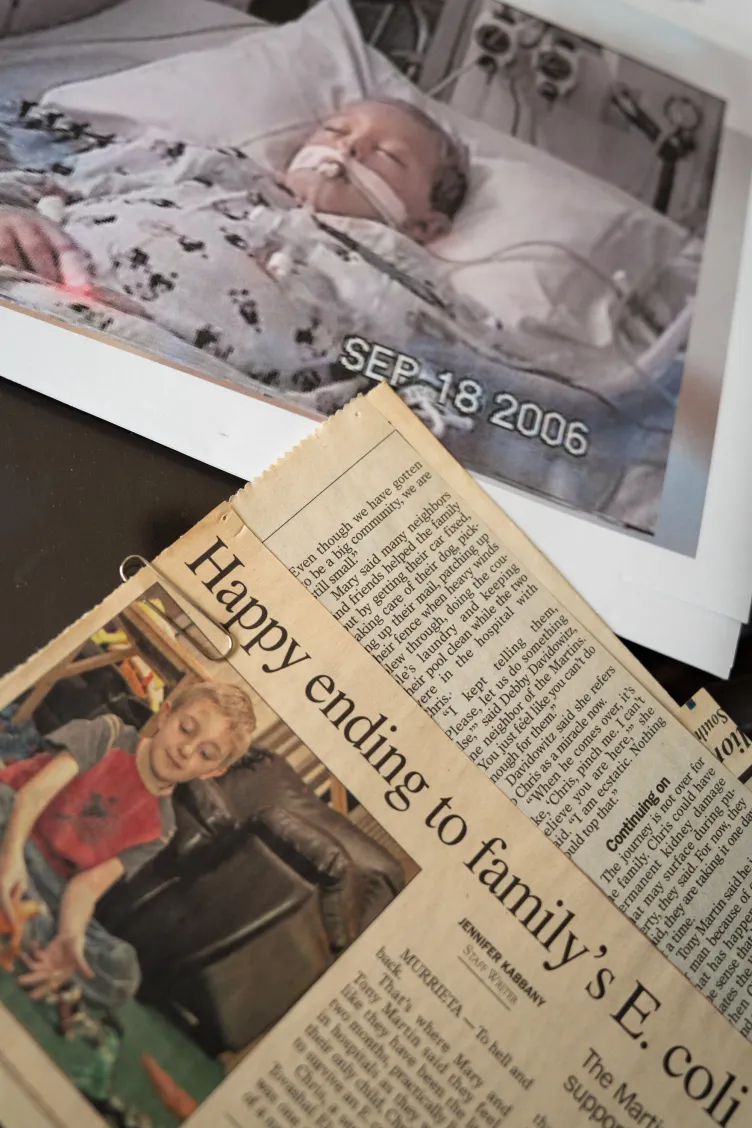 photographie d'un garçon dans un lit d'hôpital placée à côté d'une coupure de journal avec le titre commençant par « Fin heureuse pour l'E. coli de la famille ».