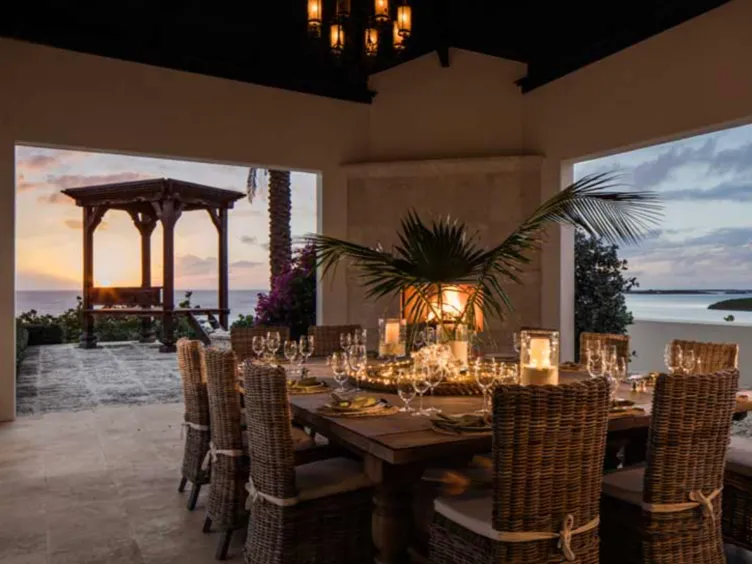 Une table à manger avec des chaises en osier dans un cadre tropical.