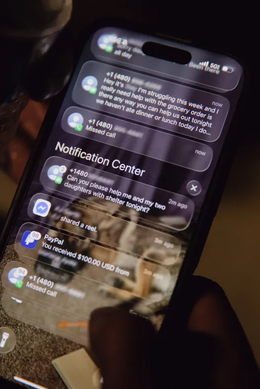 Une vue rapprochée montre l’écran d’un smartphone affichant des notifications textuelles demandant de l’aide pour se nourrir et se loger.